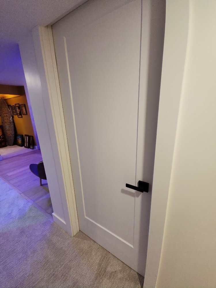 Closed white shaker-style interior door with black hardware completed by RemodelCo in a Daybreak, UT basement finish.-optimized
