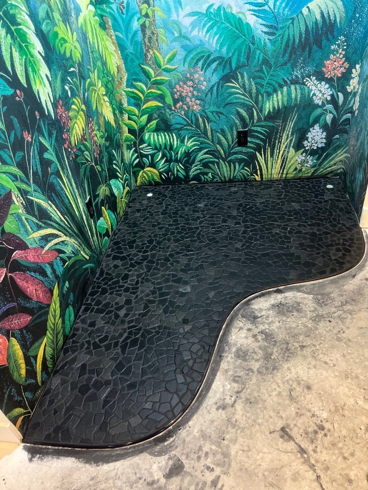 Curved black mosaic tile floor accent installed beneath tropical mural walls by RemodelCo in Daybreak, UT.-optimized