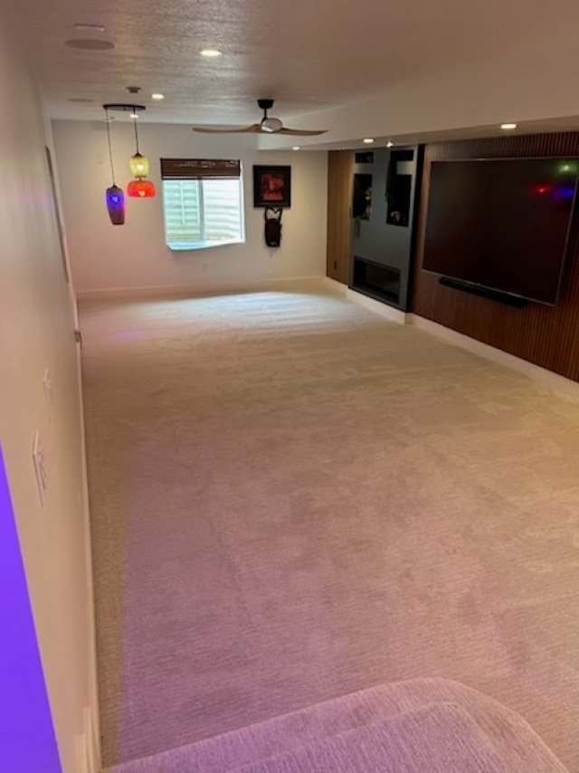 Custom basement living area featuring plush carpet and built-in media wall from a RemodelCo basement finish in Daybreak, UT.-optimized