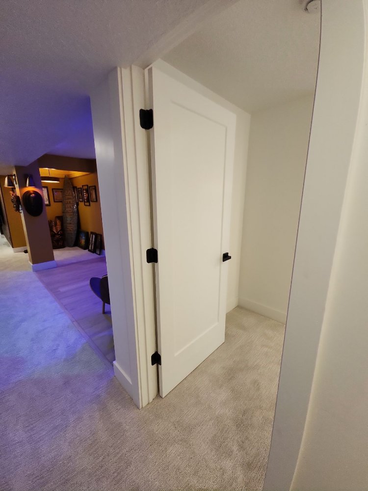 Modern basement doorway with black hinges and hardware installed during a RemodelCo basement finish in Daybreak, UT.-optimized