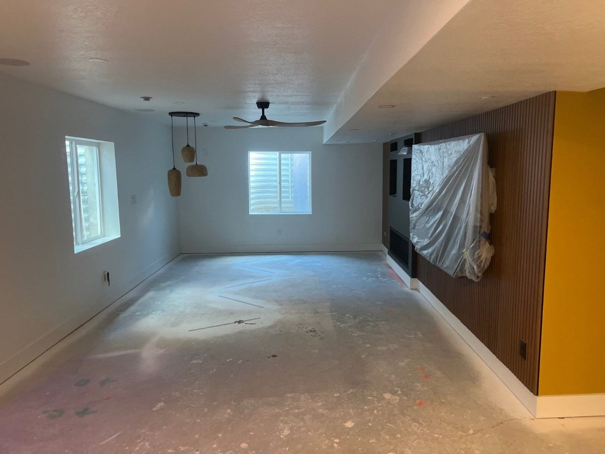 Modern basement living space under construction in Daybreak, UT by RemodelCo with decorative wood paneling and entertainment wal-optimized
