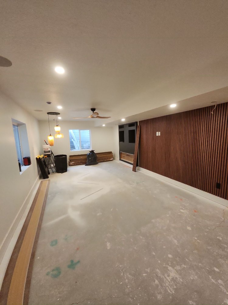 RemodelCo basement finish in Daybreak, UT featuring a custom wood slat accent wall and built-in entertainment center under const-optimized