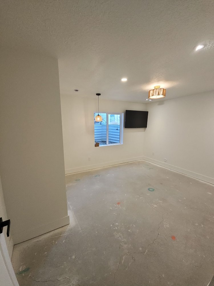 RemodelCo finished basement living space with recessed lighting and mounted television in Daybreak, UT-optimized