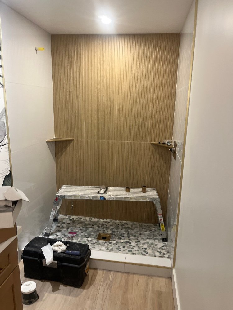 Walk-in basement shower under construction with wood-look tile accent wall by RemodelCo in Daybreak, UT.-optimized
