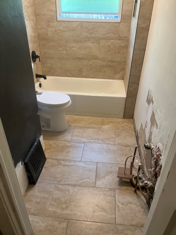 Bathroom remodel by RemodelCo in Salt Lake City, UT featuring a newly tiled tub surround, updated flooring, and modern fixtures.-optimized