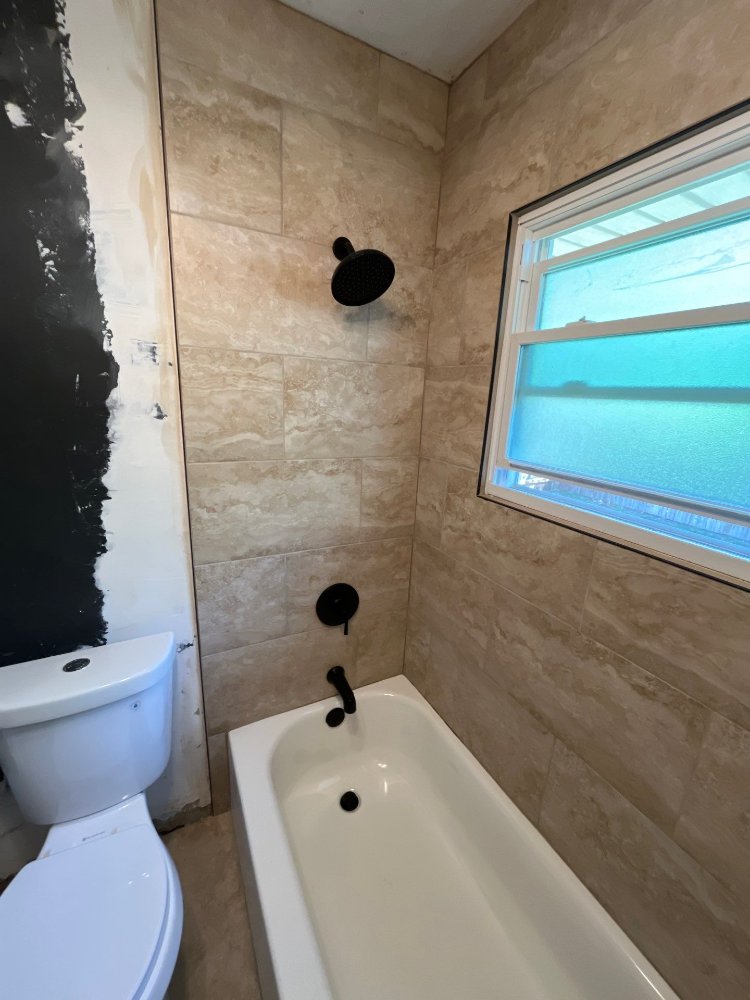 Bathroom remodel by RemodelCo in Salt Lake City, UT featuring a tiled tub surround with matte black shower fixtures and a froste-optimized