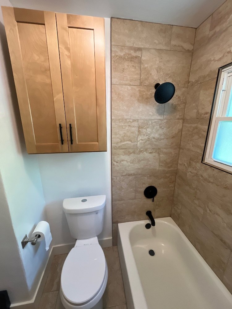 Bathroom remodel by RemodelCo in Salt Lake City, UT featuring custom overhead storage cabinetry and a tiled bathtub surround.-optimized