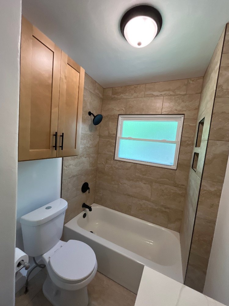 Bathroom remodel by RemodelCo in Salt Lake City, UT featuring wall-mounted cabinetry above the toilet and a tiled bathtub surrou-optimized