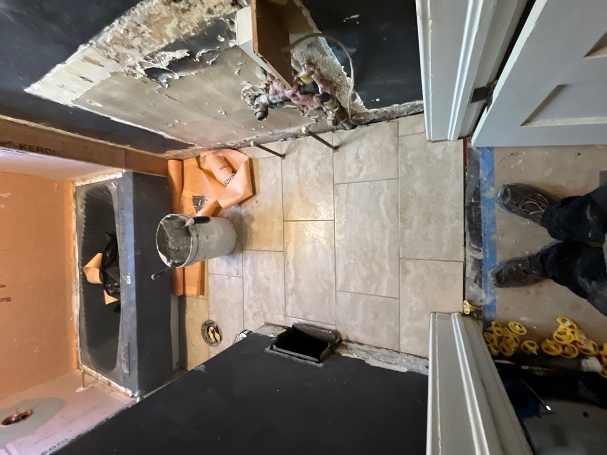 RemodelCo bathroom remodel in Salt Lake City, UT with floor tile installation progressing alongside tub surround construction.-optimized