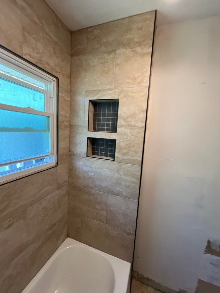 Remodeled bathroom in Salt Lake City, UT by RemodelCo showcasing built-in storage niches within a large-format tile tub surround-optimized