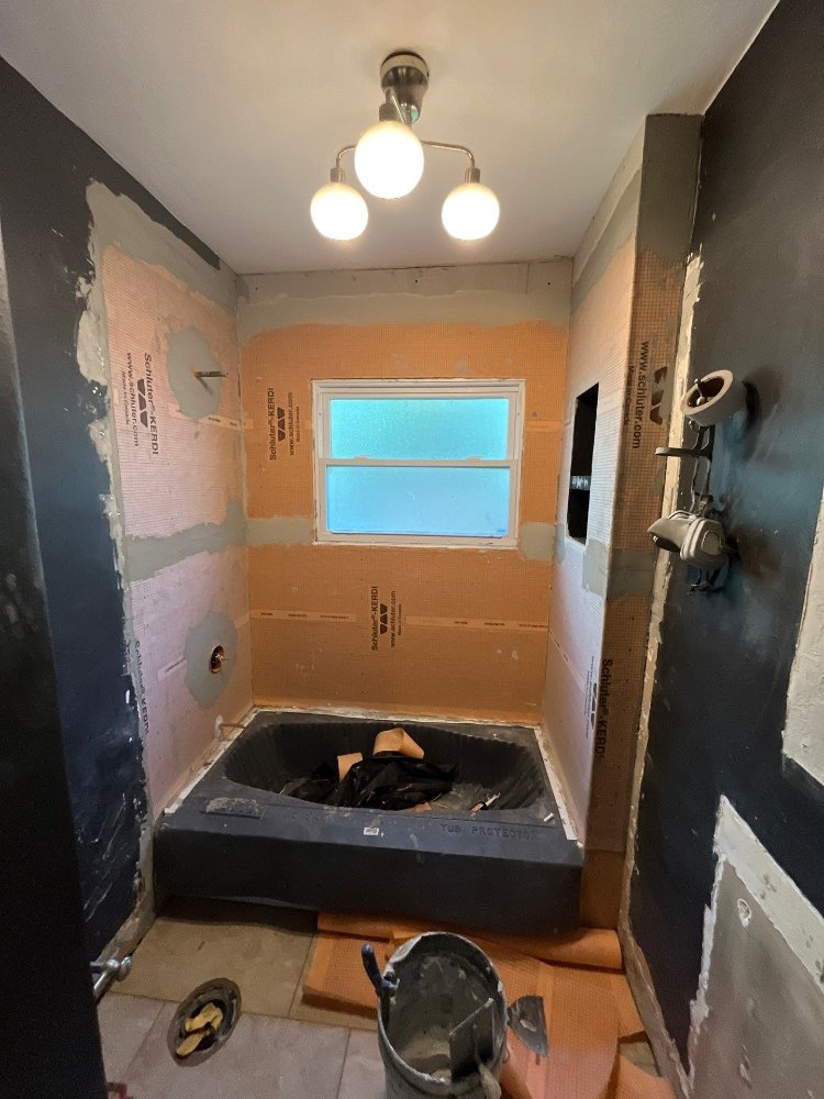 Salt Lake City bathroom remodeling project by RemodelCo showing waterproofing membrane installation around a new bathtub.-optimized