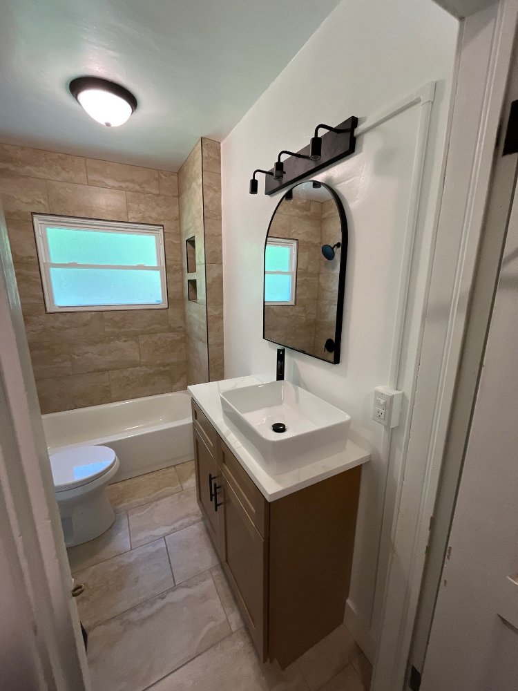 Updated bathroom renovation by RemodelCo in Salt Lake City, UT showcasing a contemporary vanity and tiled tub enclosure.-optimized