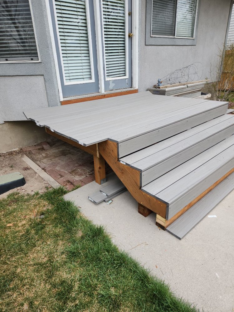 Angled view of a new gray composite deck and stair installation by RemodelCo in Midvale, UT.-optimized