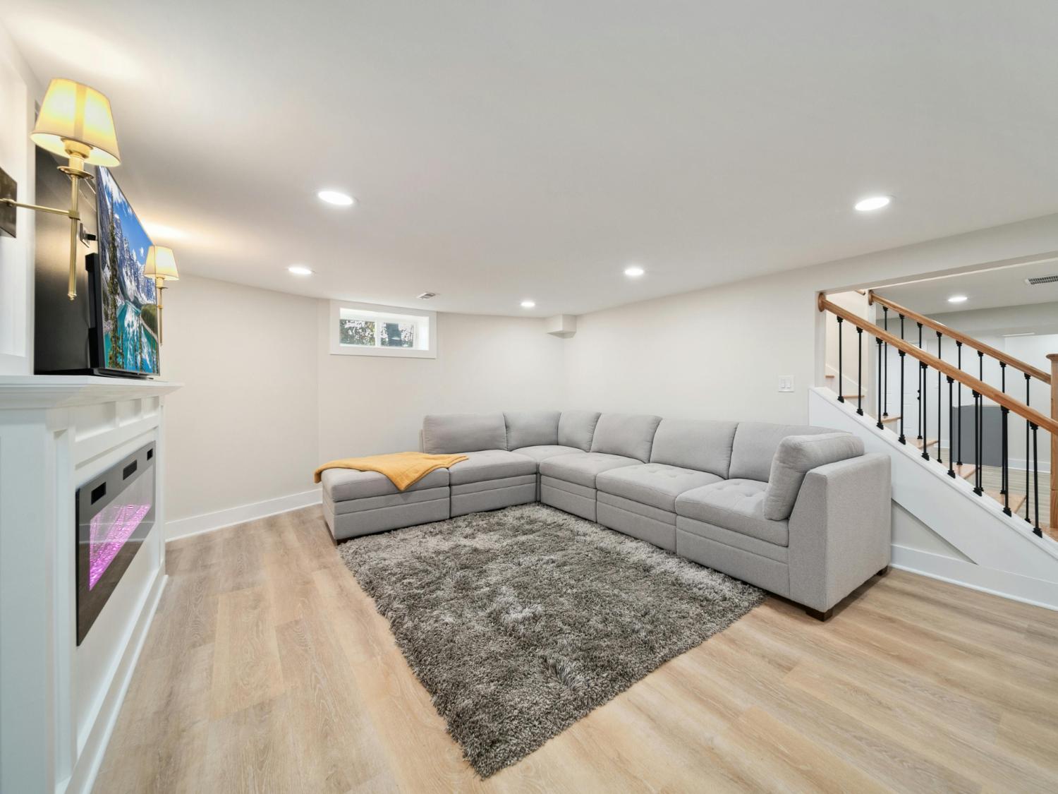 Finished basement living area with modern sectional seating and recessed lighting in a Sandy, UT basement remodeling project by -optimized