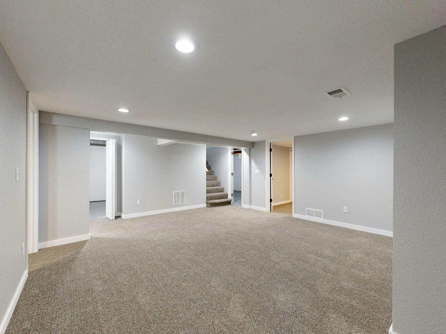 Open finished basement with plush carpeting and multiple room access points in a Sandy, UT basement remodel by RemodelCo stock-optimized