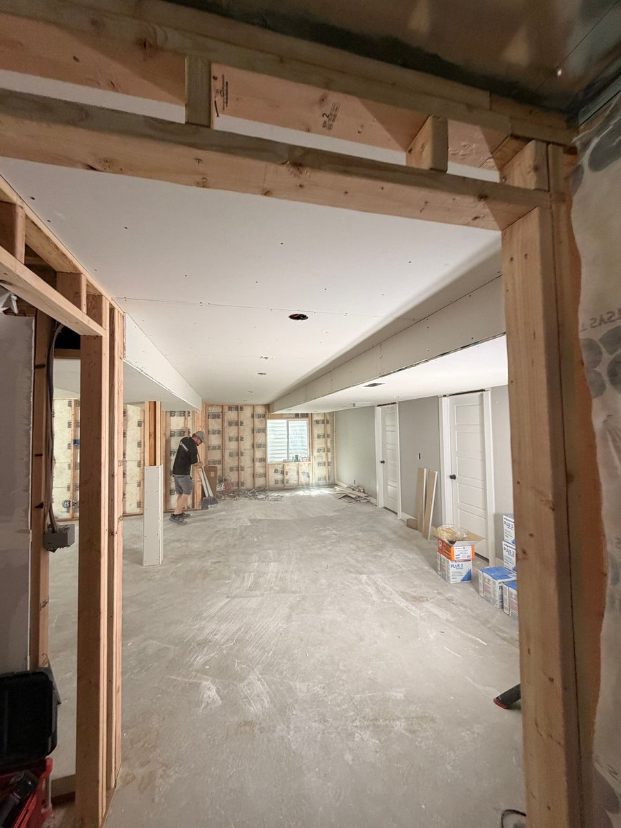 Basement finishing project during drywall installation with exposed framing and insulation along the lower walls.