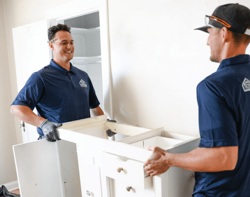 Image of employees carrying a vanity cabinet as part of a bathroom remodel