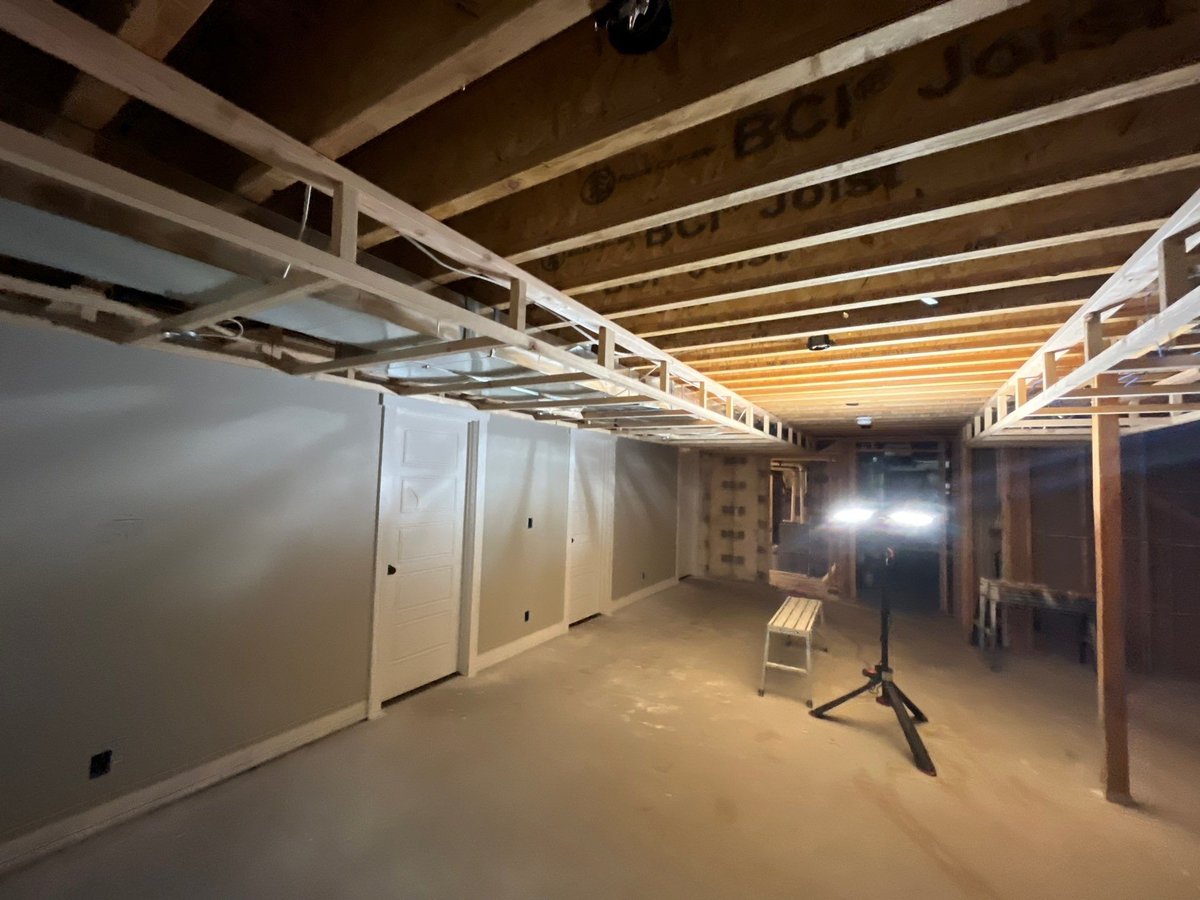 Basement finishing project during drywall installation with exposed framing and insulation along the lower walls.