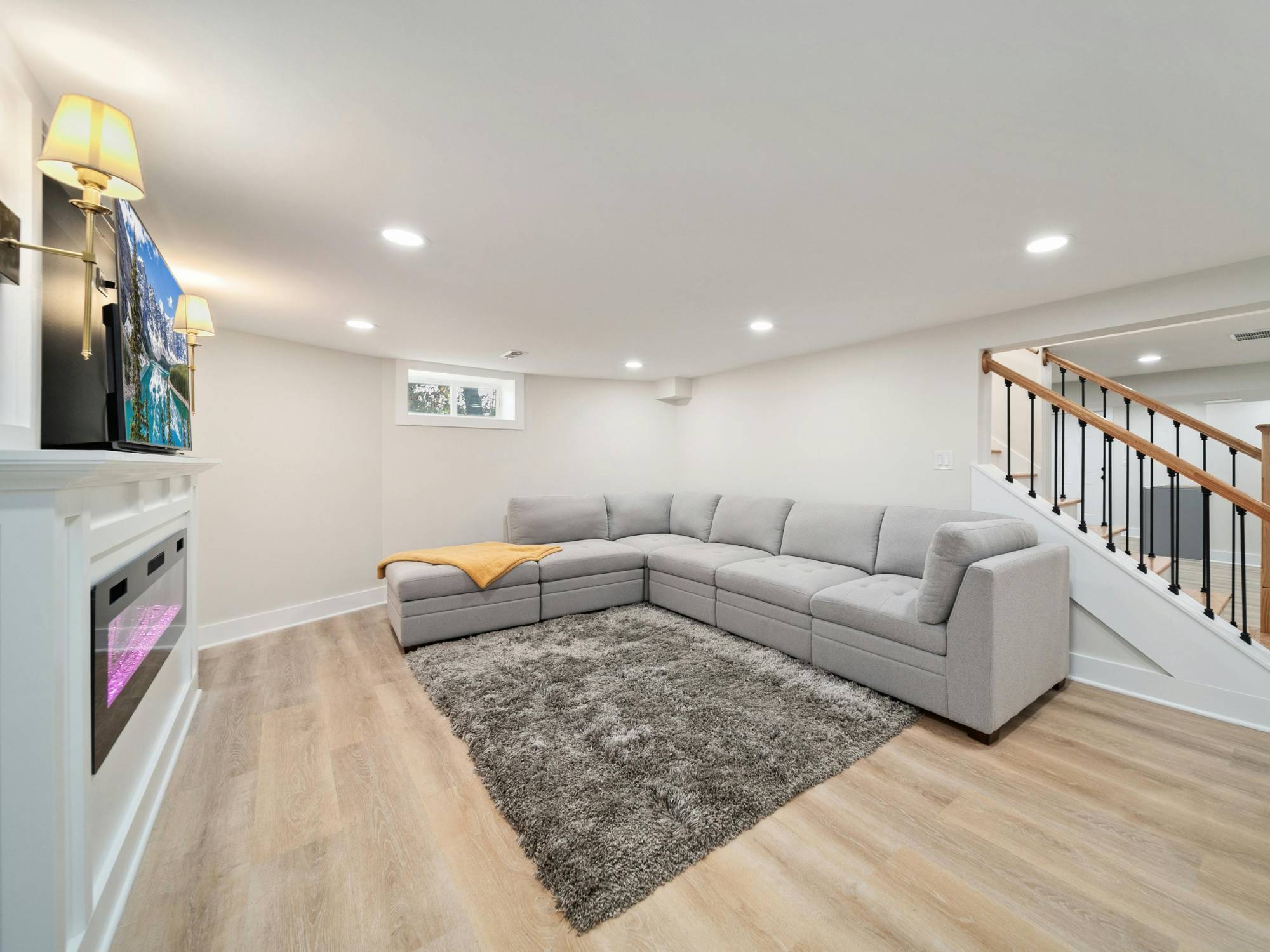 Finished basement living area with modern sectional seating and recessed lighting in a Sandy, UT basement remodeling project by -optimized