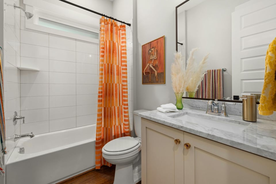 Guest bathroom with marble vanity countertop, tub shower combination, and decorative accents in a Sandy, UT bathroom remodel by -optimized