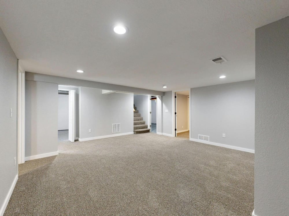 Open finished basement with plush carpeting and multiple room access points in a Sandy, UT basement remodel by RemodelCo stock-optimized