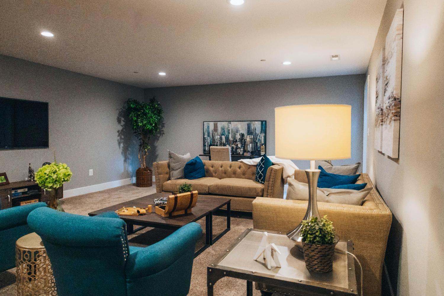 Spacious basement family room with modern furniture and neutral finishes in a Sandy, UT basement renovation by RemodelCo