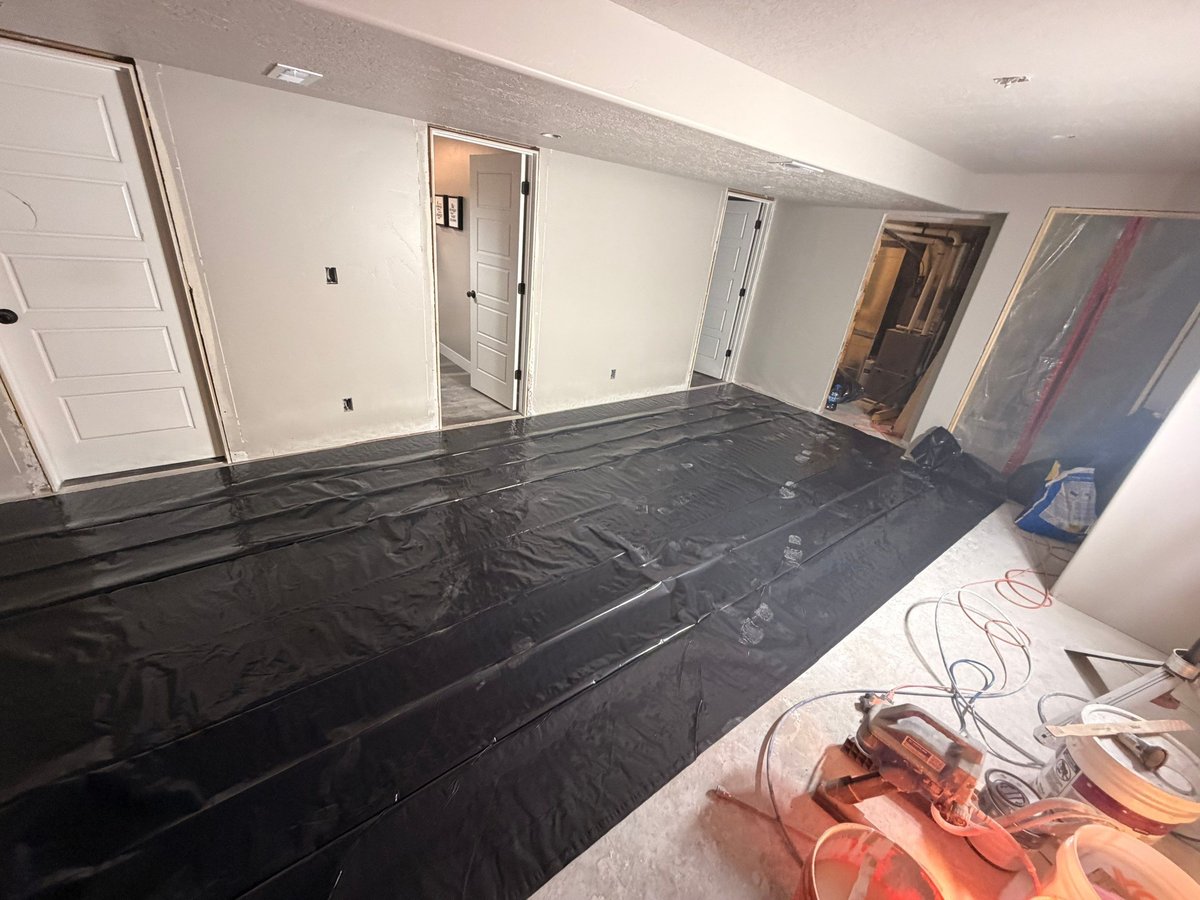 Basement renovation in progress with protective floor covering, painted walls, and interior doors installed.
