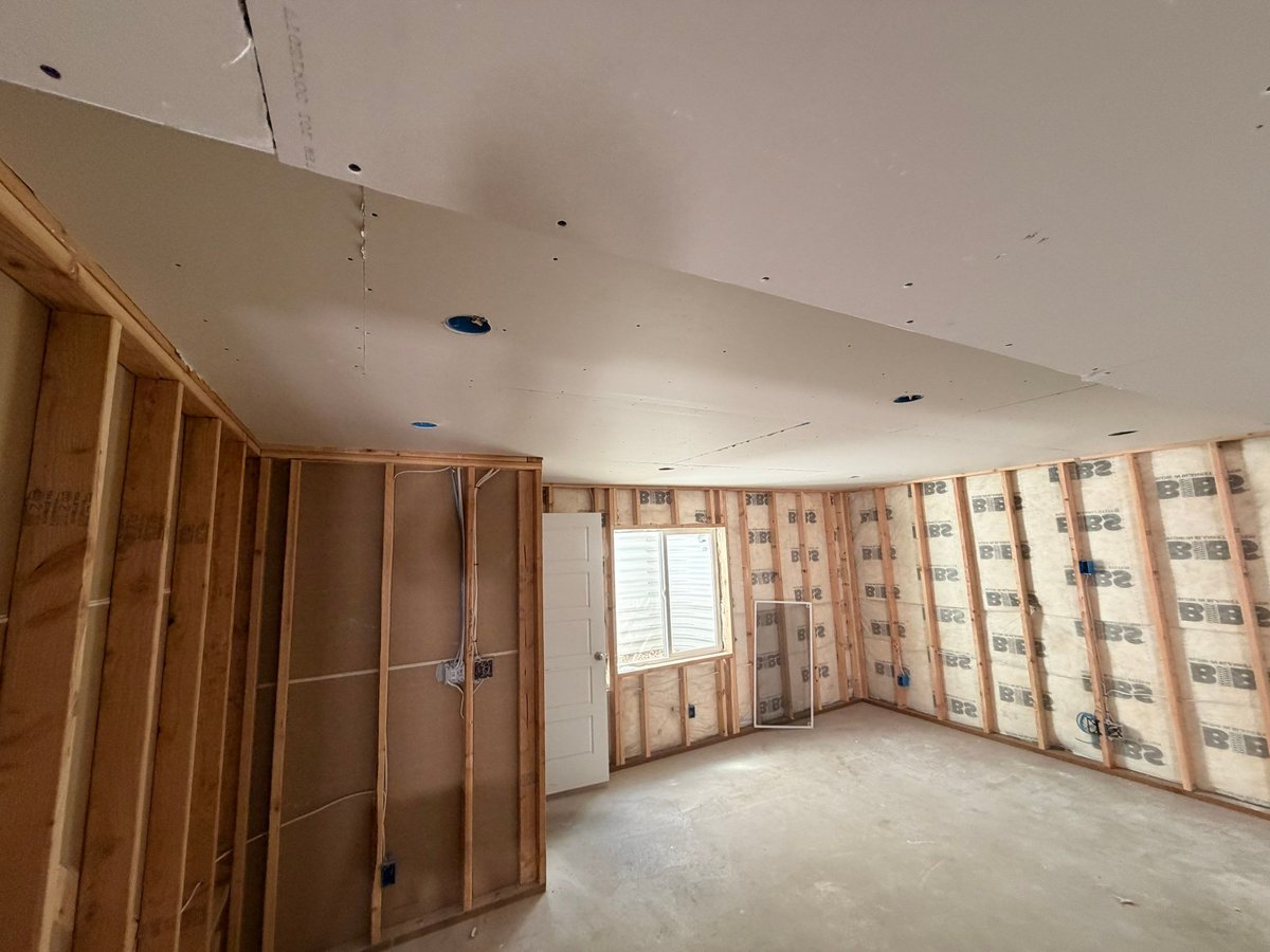 Basement finishing in progress with taped drywall, finished doors, and preparation for flooring and paint.