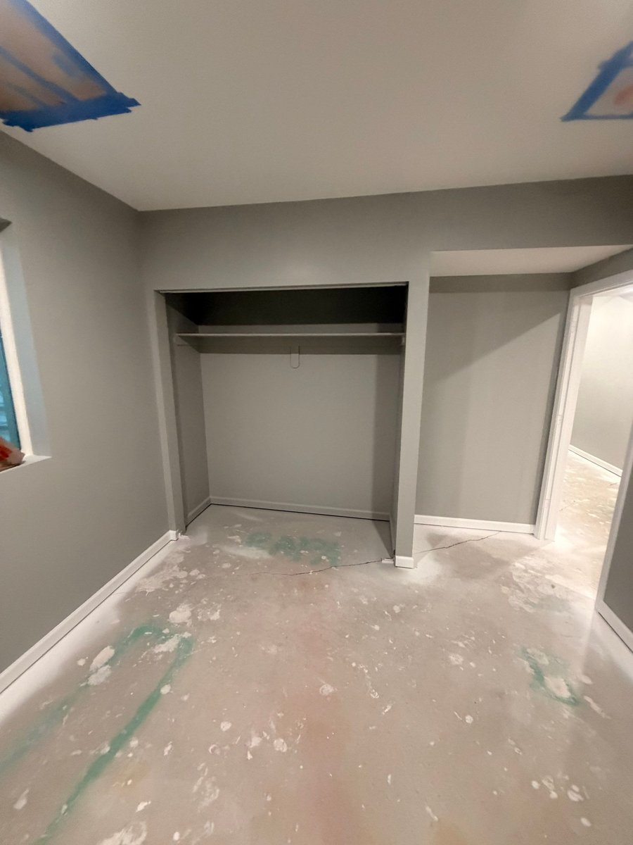 Basement bedroom closet with fresh paint, trim, and shelving during finishing.
