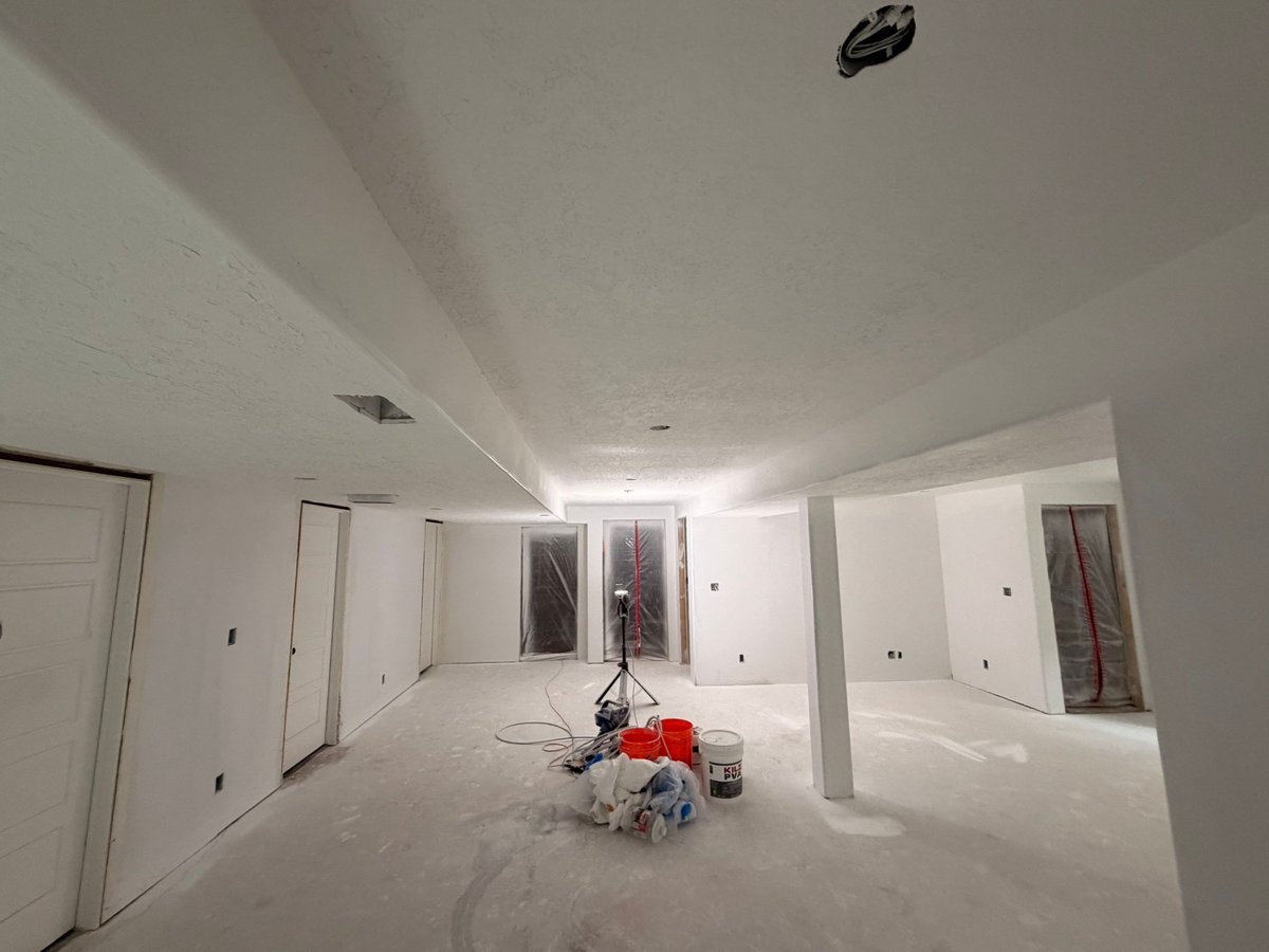 Basement finishing in progress with taped drywall, finished doors, and preparation for flooring and paint.