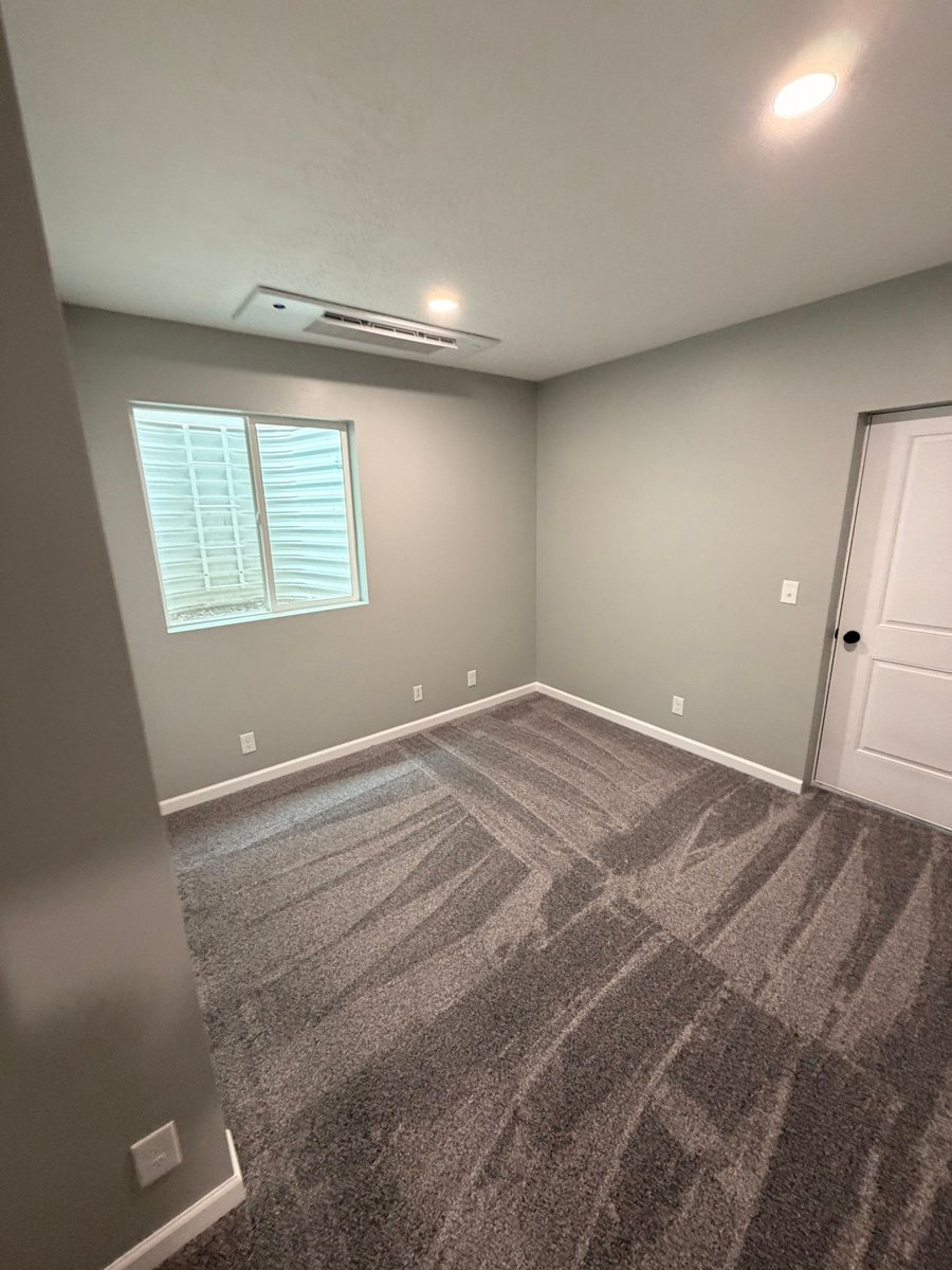 Finished basement bedroom with gray carpet, recessed lighting, and egress window.