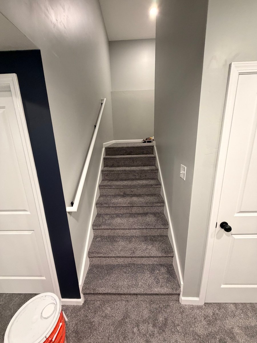 Finished carpeted basement stairs with gray walls and white trim in Herriman.