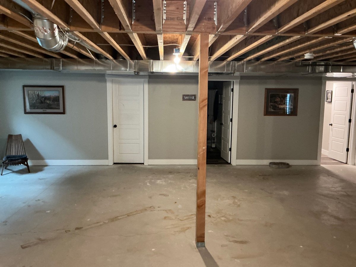 Basement finishing project during drywall installation with exposed framing and insulation along the lower walls.