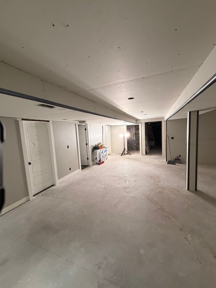 Basement finishing in progress with taped drywall, finished doors, and preparation for flooring and paint.