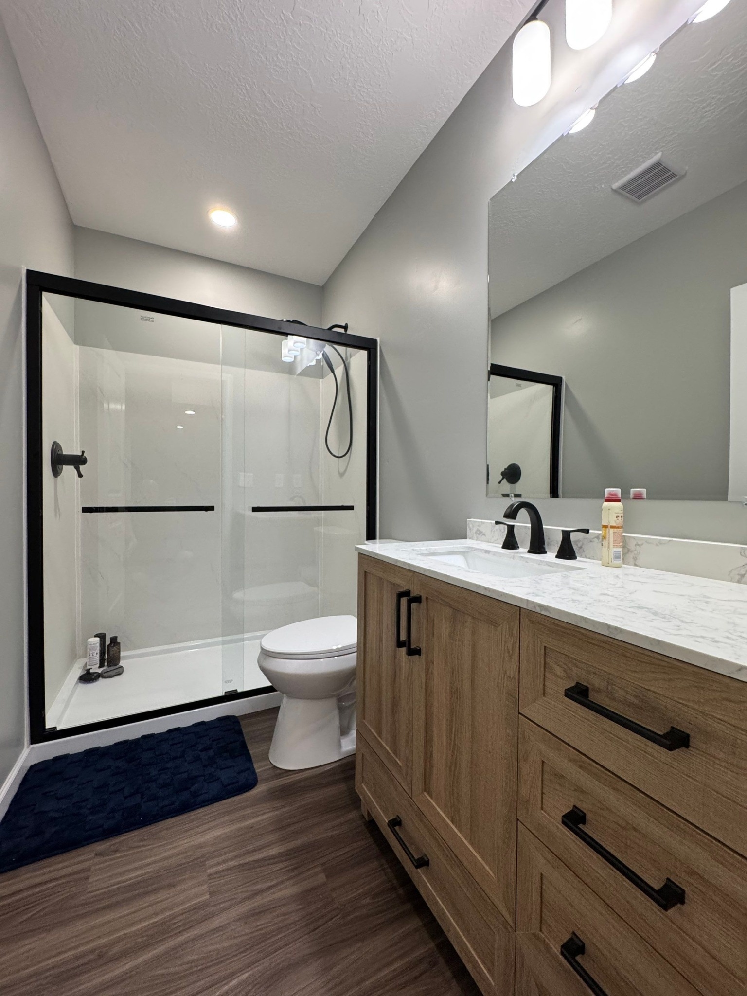 full bathroom with glass shower and wood vanity in a remodelco basement remodel in Bluffdale, UT